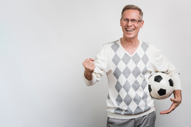 Free photo smiling man holding a soccer ball with copy-space